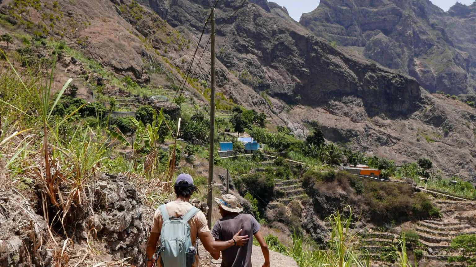 Twee wandelaars met rugzakken lopen op een wandelpad door de groene bergen van Santo Antão, Kaapverdië.
