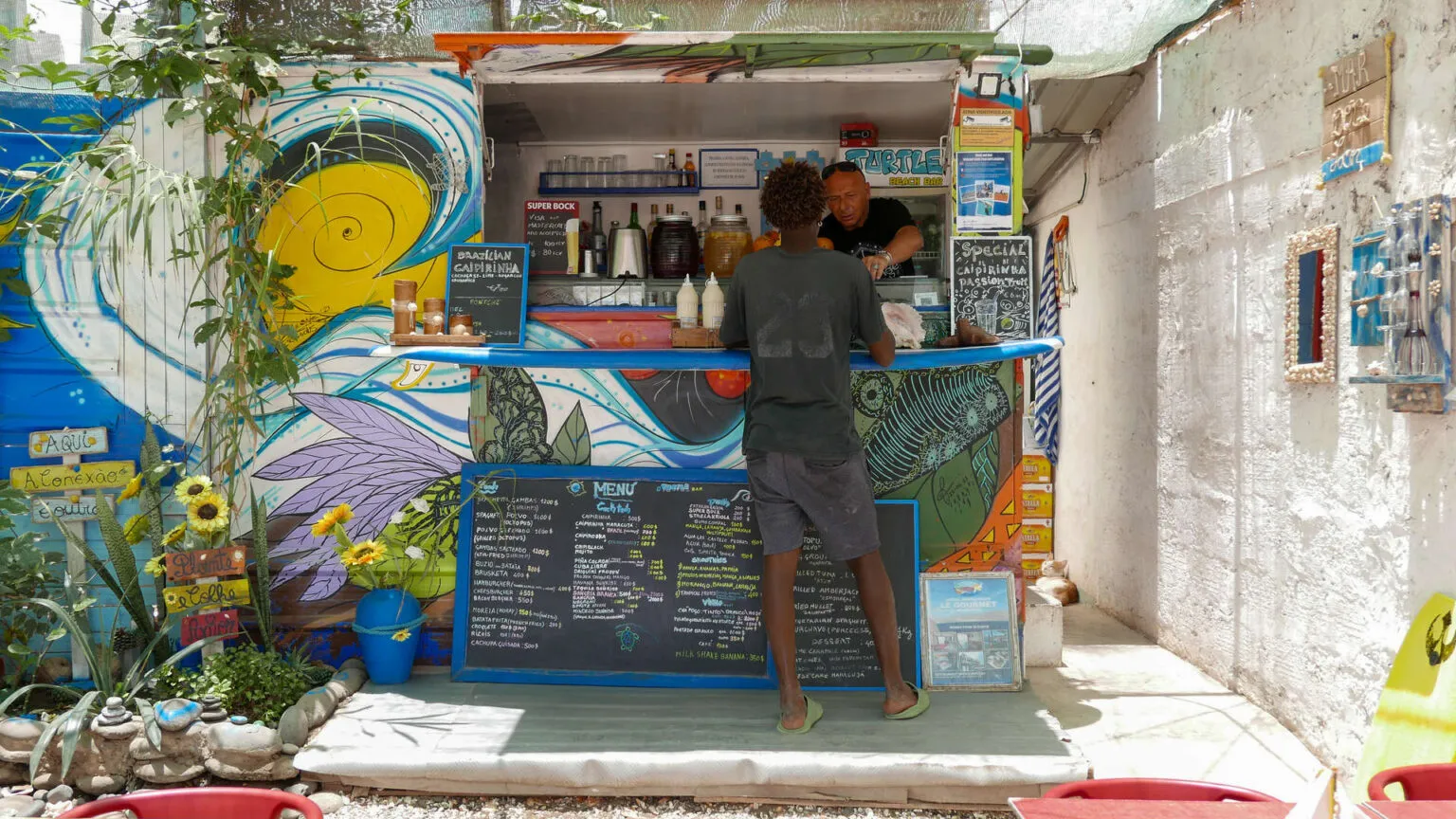 Een bezoeker bestelt eten bij een vrolijk beschilderde foodtruck op straat in São Vicente, Kaapverdië.