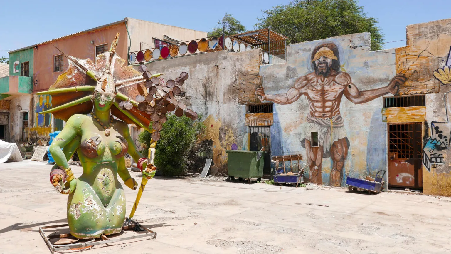 Een binnenplaats en straatbeeld met opvallende muurschilderingen van menselijke figuren op São Vicente, Kaapverdië.