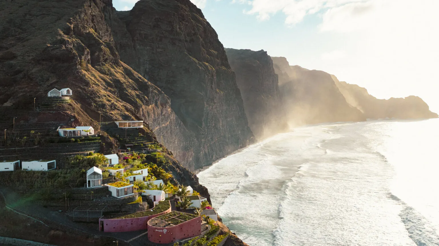 Witte huizen gebouwd op de steile kliffen van het bergachtige eiland Santo Antão, met de ruige Atlantische Oceaan op de achtergrond.