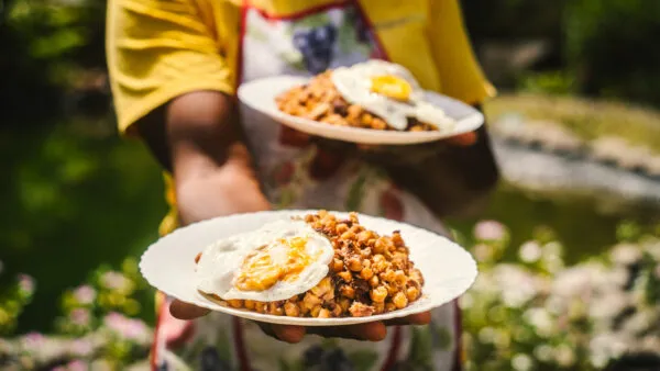 Een vrouwelijke local toont twee borden cachupa, het nationale gerecht van Kaapverdië