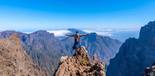 Reiziger op uitzichtpunt bij Caldera De Taburiente met bergen en blauwe lucht als achtergrond