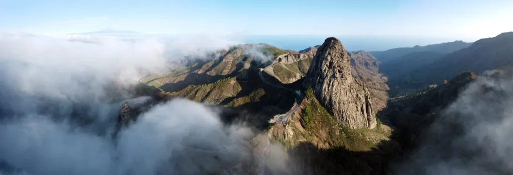 Een ruig berglandschap op La Gomera met steile rotsformaties, weelderige groene pieken en drijvende mistwolken in het dal.
