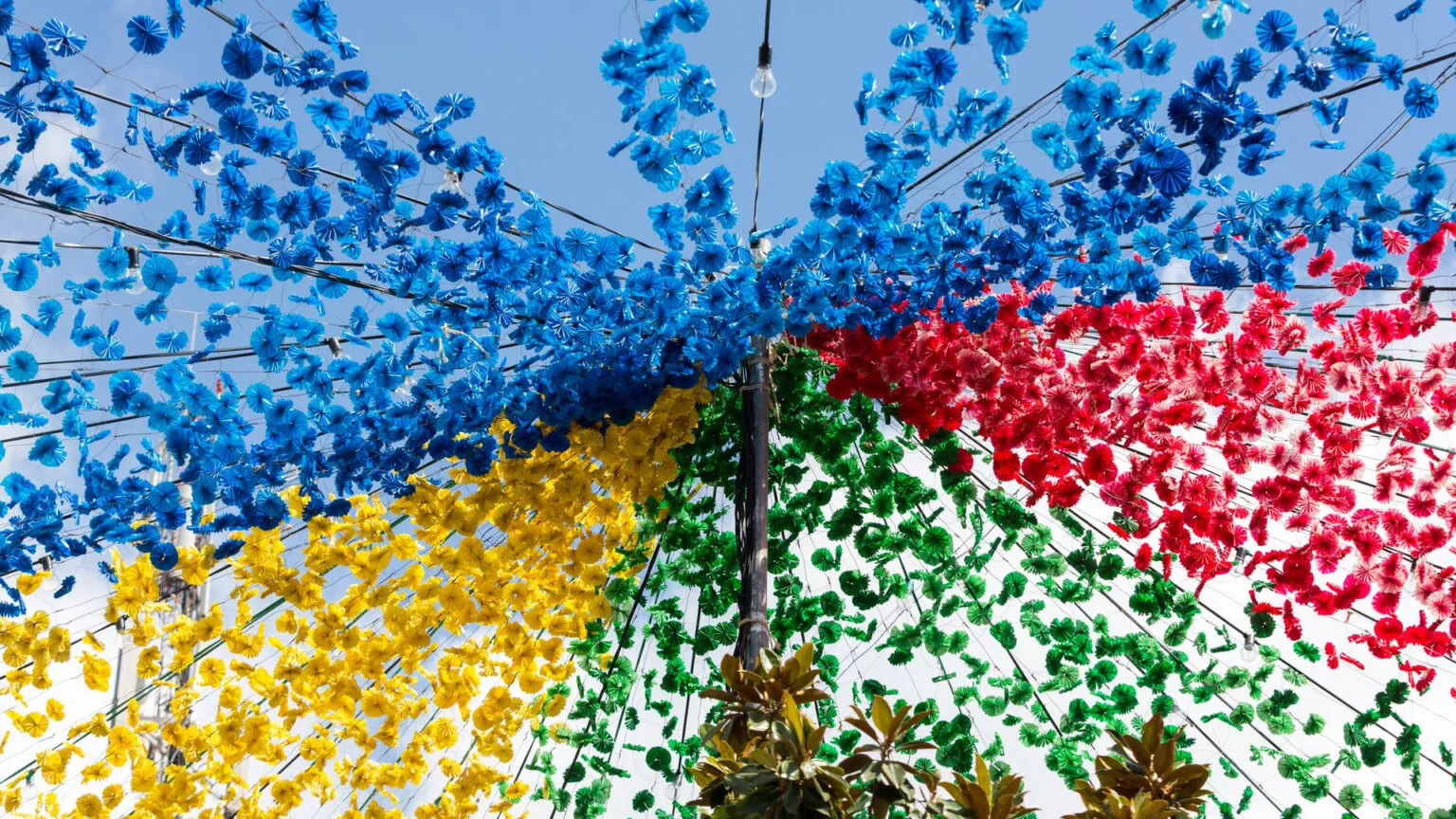 Straatversiering van kleurrijke blauwe, rode, gele en groene papieren bloemen die boven de straat hangen in Câmara de Lobos op Madeira.