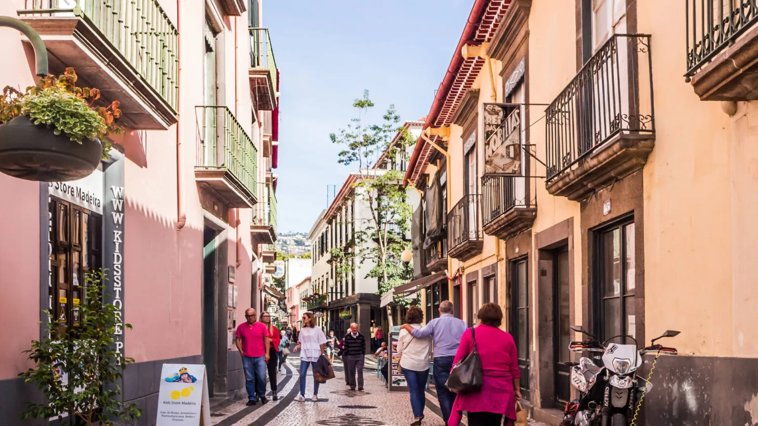 Wandelaars slenteren door een smalle, sfeervolle straat met kleurrijke gevels en balkonnetjes in het oude centrum van Funchal op Madeira.