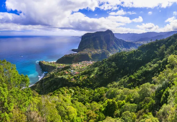 Weelderig groene kustheuvels en de imposante rots Penha d'Águia aan de diepblauwe oceaan bij Santana op Madeira