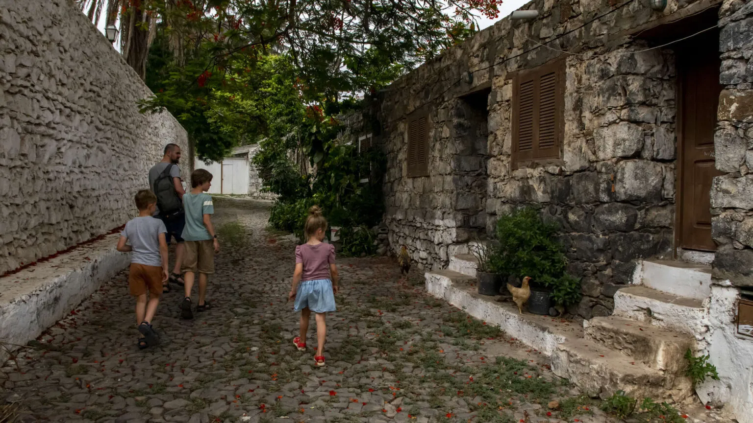 Twee kinderen lopen over een authentiek klinkerstraatje langs traditionele stenen huizen op Kaapverdië.