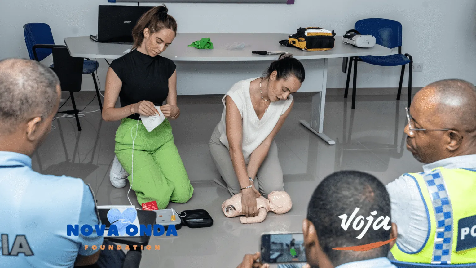 Twee vrouwen voeren een reanimatie-instructie uit op een reanimatiepop op de vloer tijdens een EHBO-training van het Nova Onda impactproject op Santo Antão, Kaapverdië.