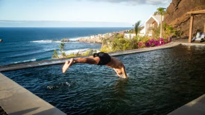 Een man neemt een duik in een zwembad met uitzicht op de zee, Santo Antão, Kaapverdië