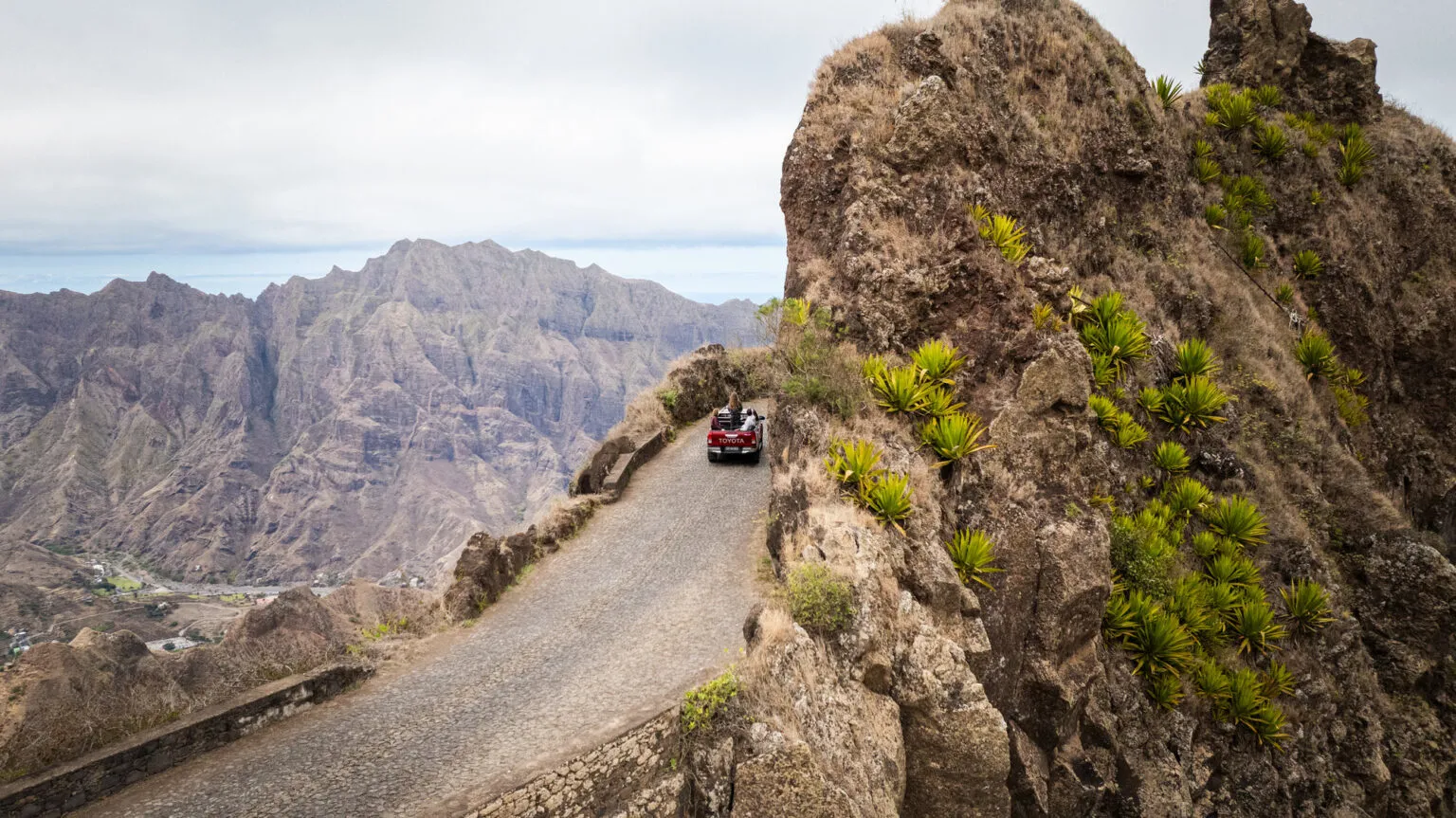 Auto rijdt over een smalle kronkelende bergweg langs steile rotspartijen op het eiland Santo Antão in Kaapverdië