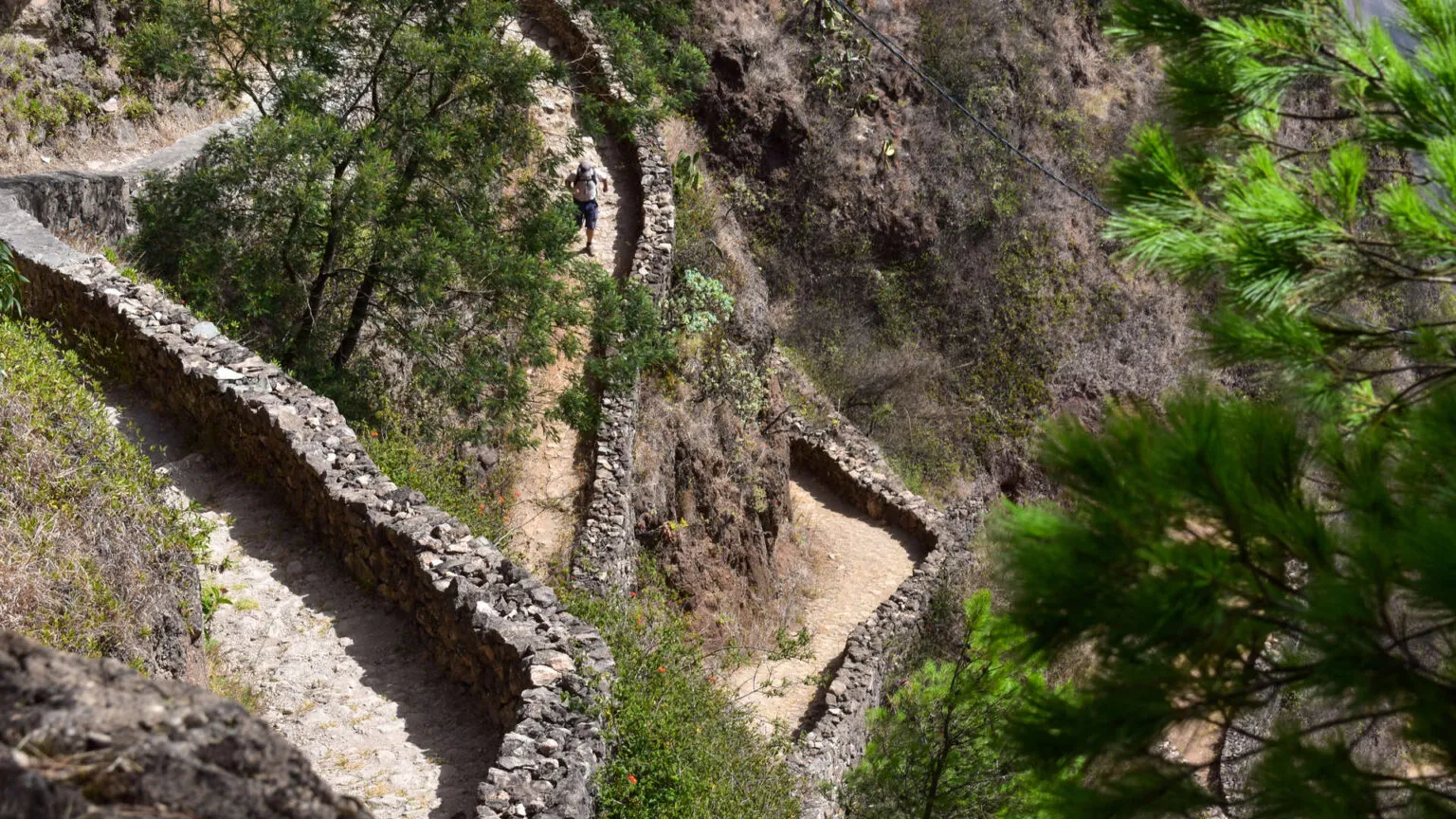 Slingerend wandelpad door een steile rotsachtige krater met groene begroeiing op het eiland Santo Antão in Kaapverdië
