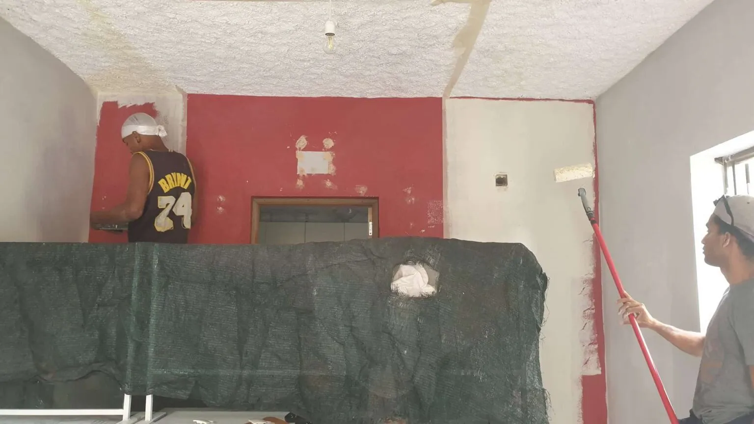 Een binnenruimte in aanbouw voor het project Pastelaria Neu, met gestucte wanden en afgedekte meubels tijdens de renovatie.
