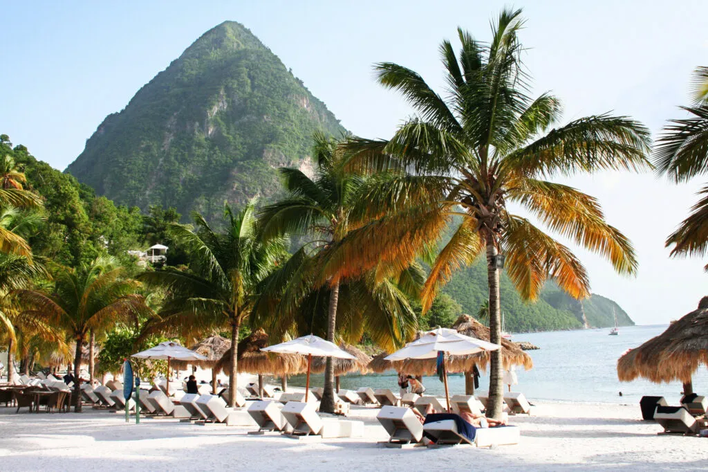Strandbedjes en parasols op het witte zandstrand van Saint Lucia met uitzicht op de iconische Pitons.