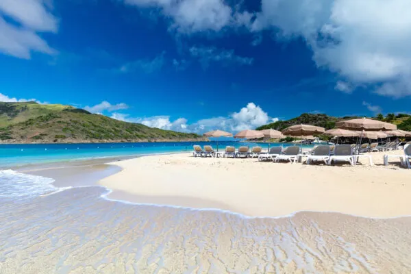 Wit zandstrand met kristal helder water, zonnebaden met groene bergen als achtergrond