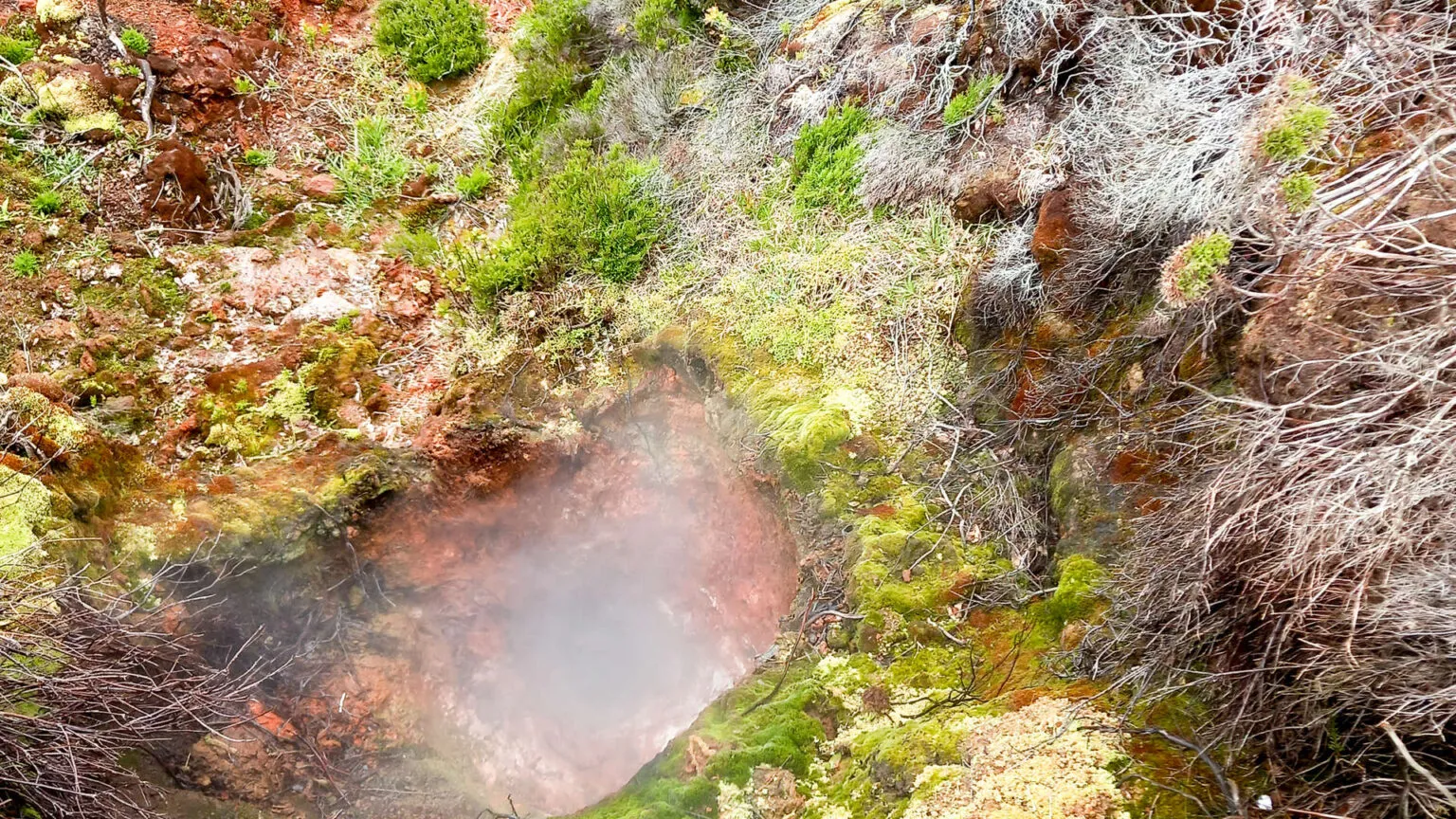 Close-up van opstijgende stoom en zwavelafzettingen tussen mos en vulkanisch gesteente in het geothermatische gebied Furnas do Enxofre op Terceira, Azoren.