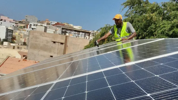 Een lokale monteur installeert zonnepanelen op het dak van een van Voja's accommodaties op het eiland Santiago