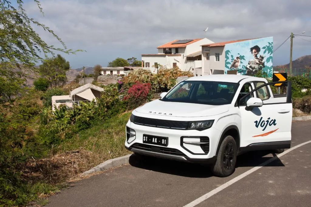 Een elektrische auto van Voja met op de achtergrond het binnenland van het eiland Santiago