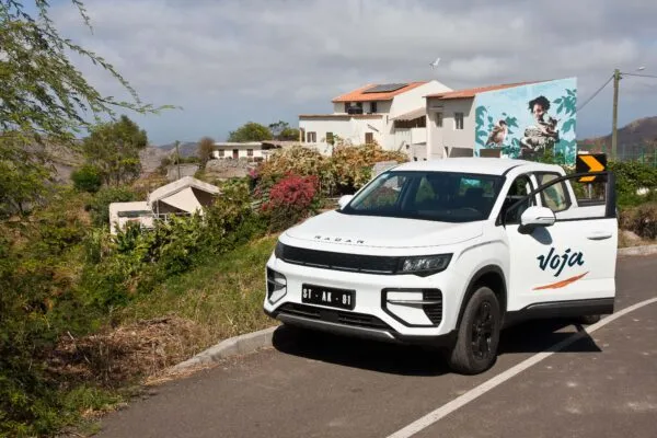Een elektrische auto van Voja met op de achtergrond het binnenland van het eiland Santiago