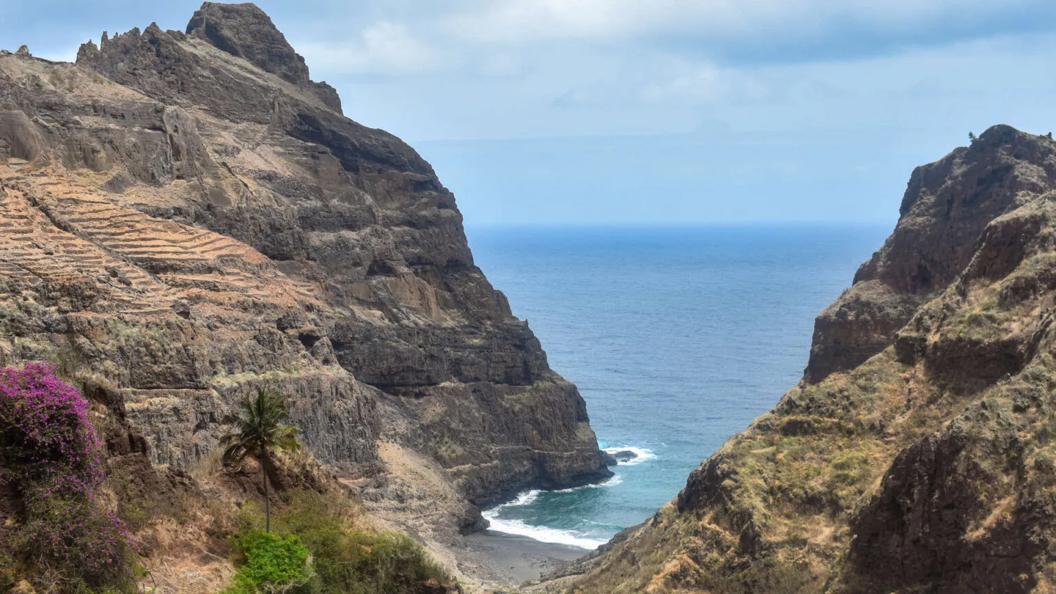 Steile rotswanden die uitlopen in een beschutte baai met de diepblauwe oceaan nabij Fontainhas op Santo Antão, Kaapverdië.