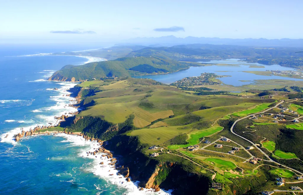 Panoramisch bovenaanzicht van de groene hevels, ruige rotskust en de lagune van Knysna langs de Garden Route in Zuid-Afrika.