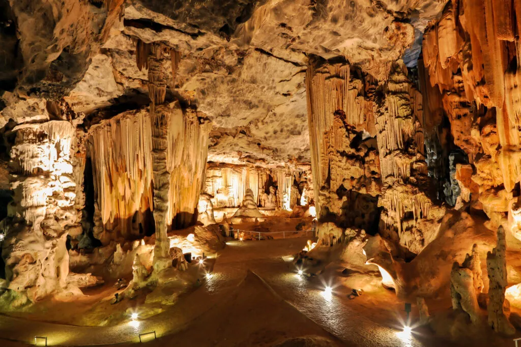 Sfeervol verlichte ondergrondse gang in de Cango Caves nabij Oudtshoorn met enorme stalactieten en stalagmieten.