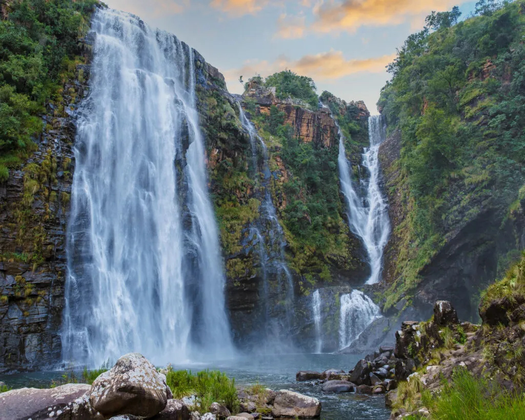 Krachtige watervallen storten naar beneden langs rotsachtige kliffen in een groen dal bij de Lisbon Falls langs de Panoramaroute in Zuid-Afrika.