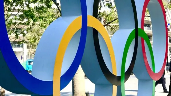 Close-up van een grote sculptuur van de iconische vijf Olympische ringen in blauw, geel, zwart, groen en rood in de openbare ruimte.