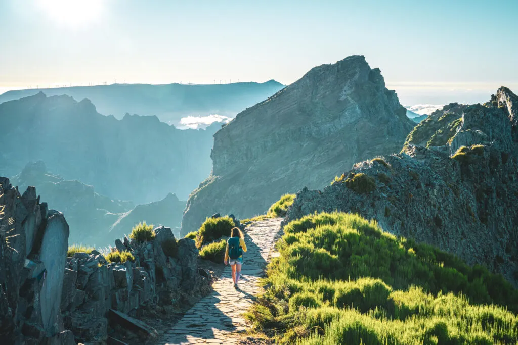 Sporty Woman With Backpack Walking Along Super Scenic Hike Trail On Pico Do Ariero In The Evening Sun. Verade Do Pico Ruivo, Madeira Island, Portugal, Europe.
