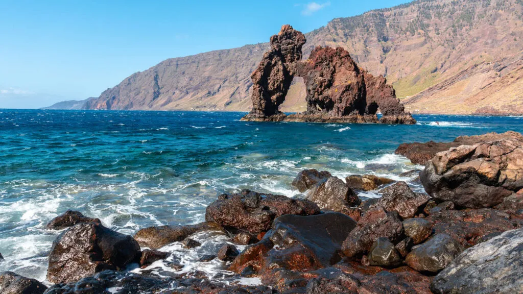 Markante vulkanische rotsboog Roque de Bonanza in de helderblauwe oceaan aan de rotsachtige kust van Las Playas op El Hierro