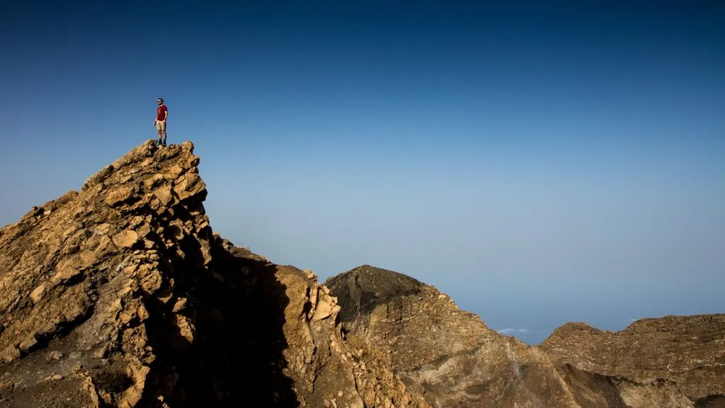 Een mannelijke reiziger geniet na het beklimmen van de Pico do Fogo van het uitzicht op het vulkanische landschap