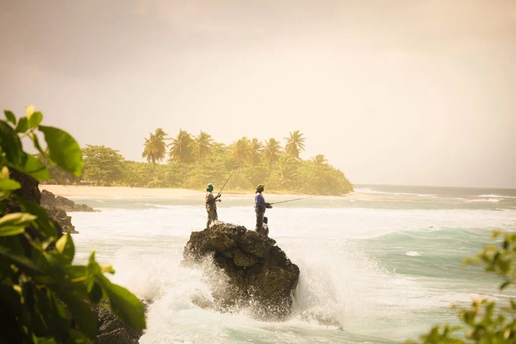 Twee vissers op een rots in de wilde zee bij Anse Bertrand in Guadeloupe.