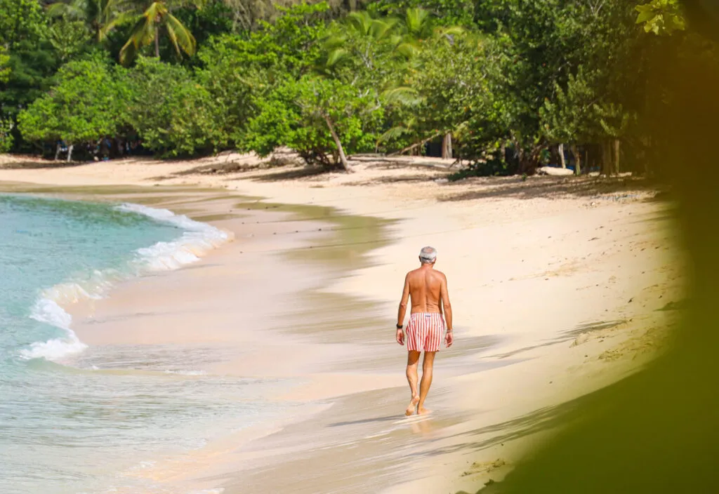 Aanzicht van een man die een strandwandeling maakt langs de zee op het zandstrand van Port Louis in Guadeloupe.
