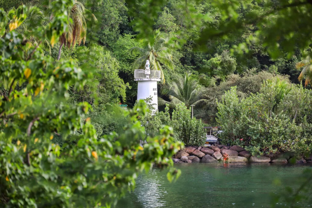 Een witte vuurtoren bij de groen begroeide kust bij de vissersplaats Duché in Guadeloupe.