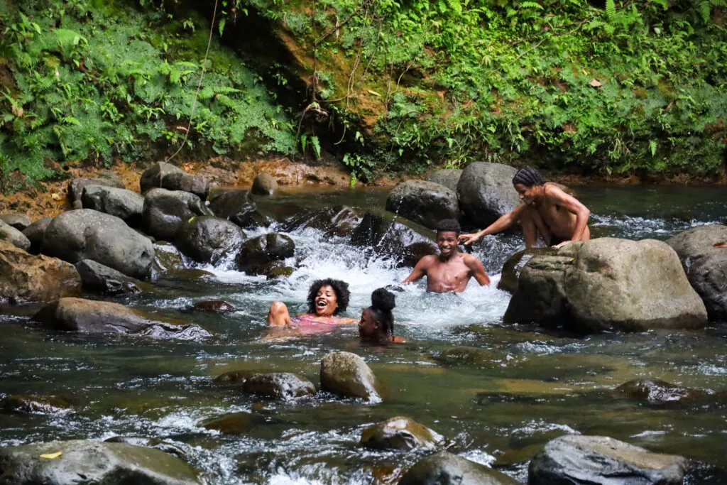 Een groep mensen zwemt en ontspant in de rivier te midden van de jungle bij Maison de la Forêt in Guadeloupe.