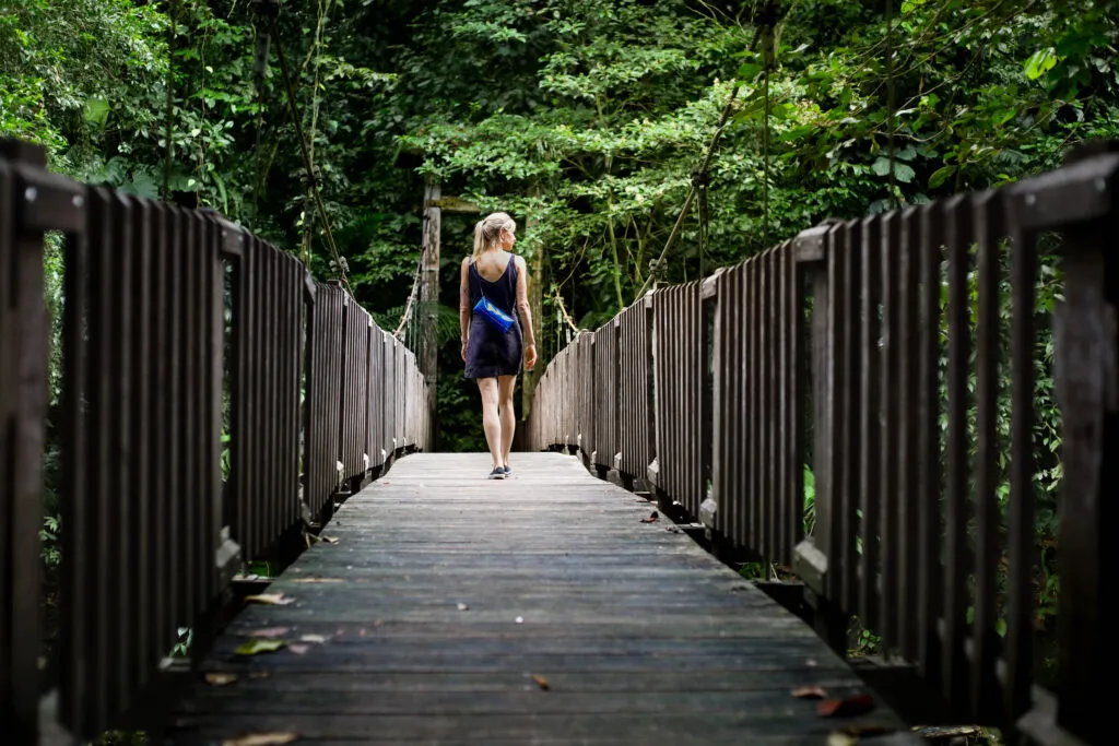 Een vrouw loopt over een houten brug door het dichte tropische bos bij Maison de la Forêt in Guadeloupe.