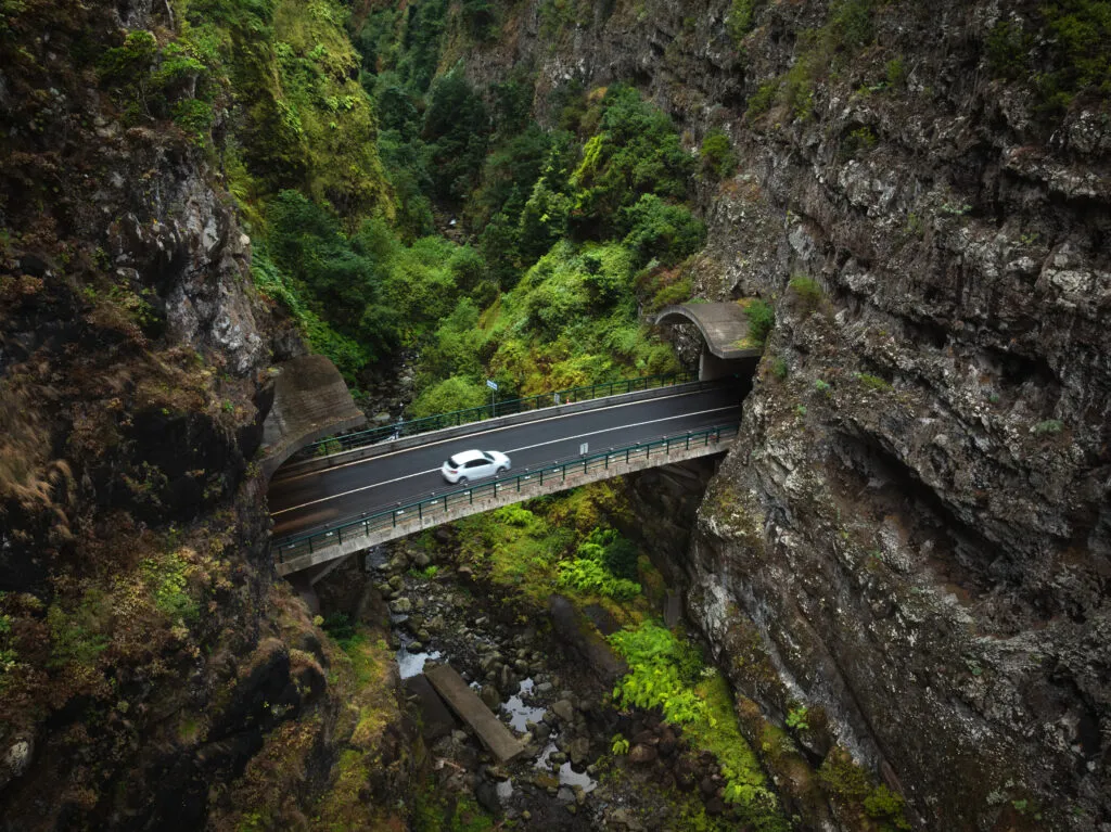 Witte auto die door de binnenlanden van Madeira rijdt