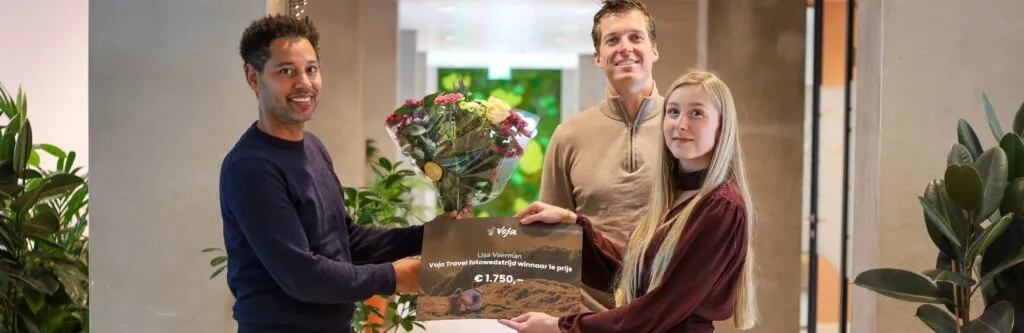 Voja-founder Joshua van Eijndhoven overhandigt een cheque van €1750 aan de winnares van de Voja Fotowedstrijd 2026
