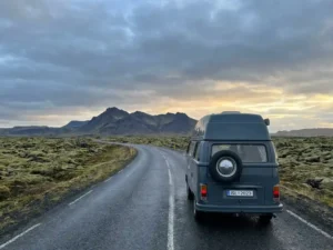 Campervan op IJslands Ring Road omgeven door mosrijke lavavelden en een dramatisch vulkanisch landschap onder bewolkte hemel.