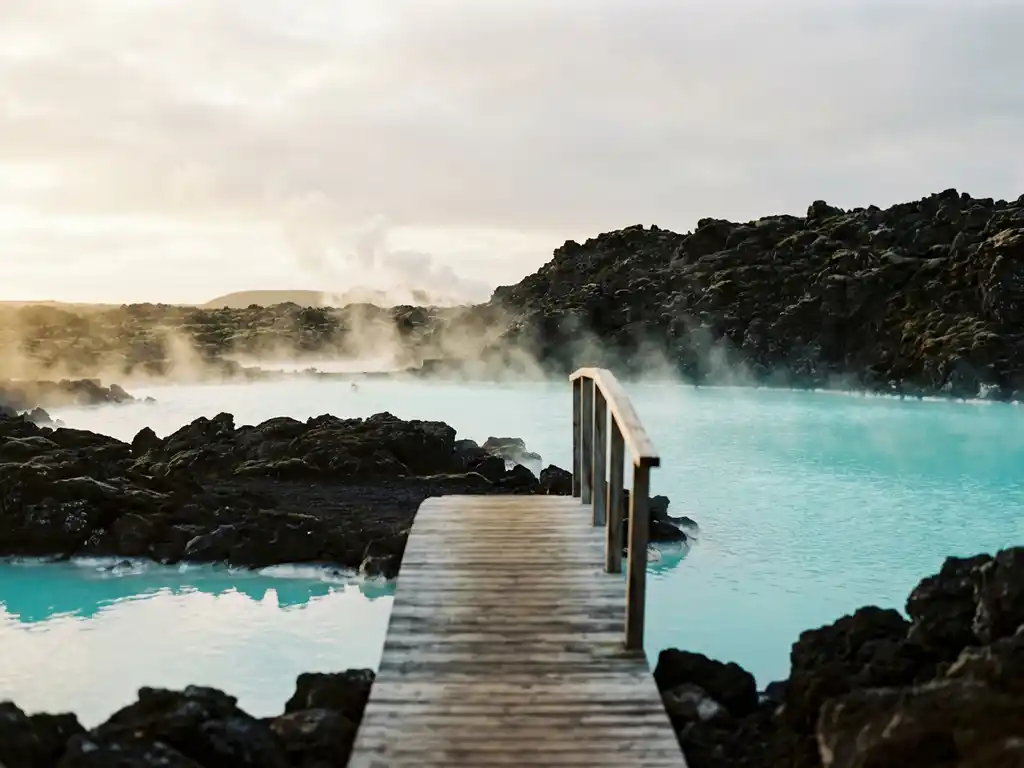 Dampende geothermische hete bron met turquoiseblauw water, omringd door zwart vulkanisch lavagesteente in IJsland, met houten loopbrug.