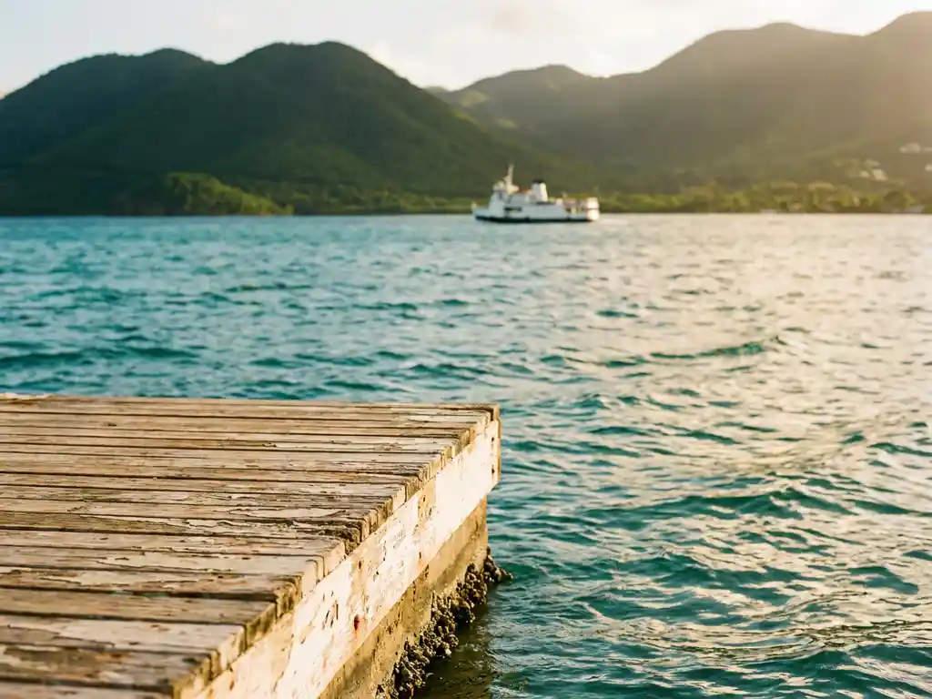 Verouderde houten steiger reikt uit over turquoise Caribisch water bij Martinique, met weelderige vulkanische heuvels en een veerboot op de achtergrond.