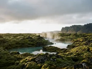 Verlaten lavaveld met mos en dampende warmwaterbron, omgeven door basaltrotsen onder een arctische lucht in IJsland.