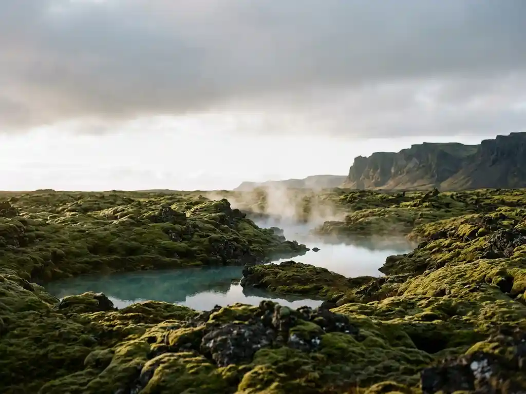 Verlaten lavaveld met mos en dampende warmwaterbron, omgeven door basaltrotsen onder een arctische lucht in IJsland.