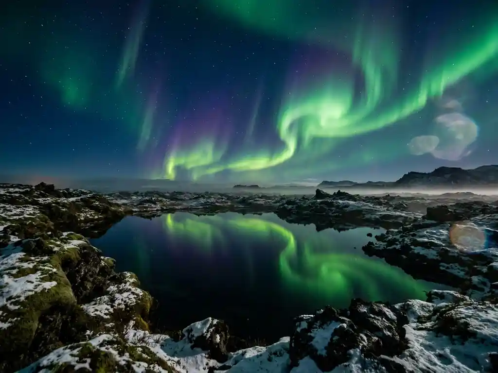 Noorderlicht in groen en violet boven IJslands lavaveld, weerspiegeld in een spiegelgladde pool, met besneeuwde mosrotsen op de voorgrond.