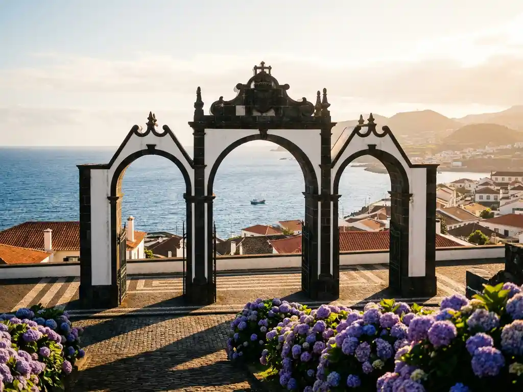 Witte en zwarte basalten poortbogen van Ponta Delgada met de Atlantische Oceaan op de achtergrond, terracotta daken en paarse hortensia's in gouden avondlicht.