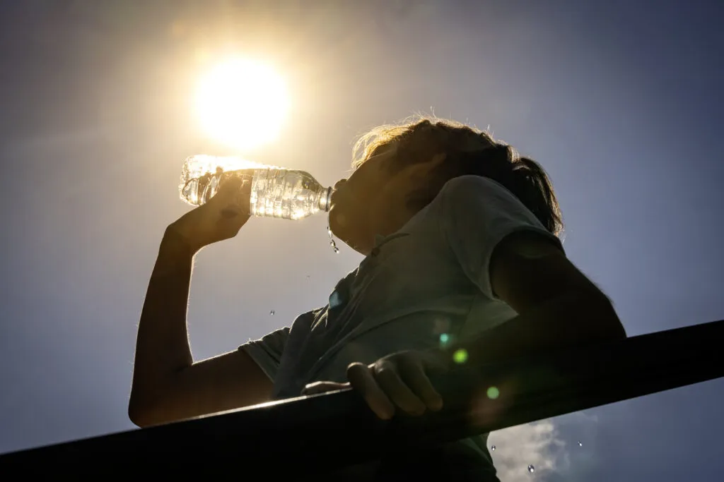 Boy drinking water from a bottle on a sunny hot day.
